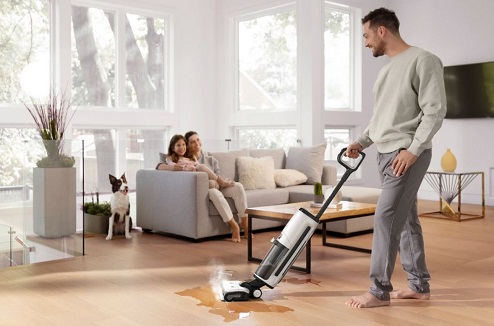 naopé Homme passe un aspirateur balai laveur sa famille et son chien sont à côté