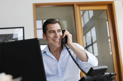 Un homme au téléphone depuis un bureau avec un téléphone fixe