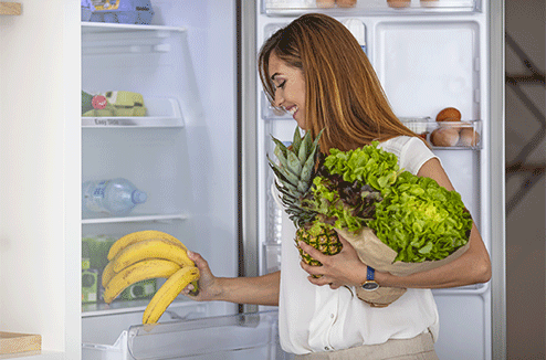 Une femme range les courses au frigo