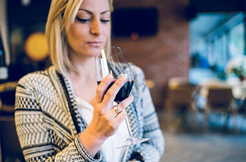 Une femme tient un verre de vin rouge