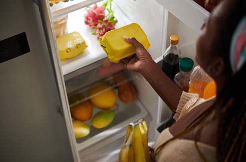 Femme déposant des œufs dans un frigo