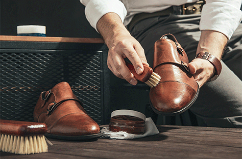 Un homme nettoie des chaussures en cuir