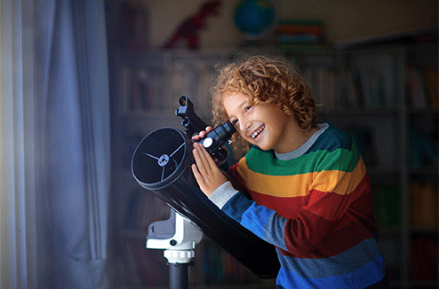 Un enfant observer le ciel avec son télescope