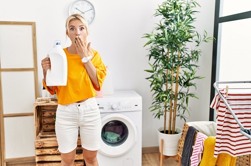 Une femme avec un air étonné tient un flacon de lessive