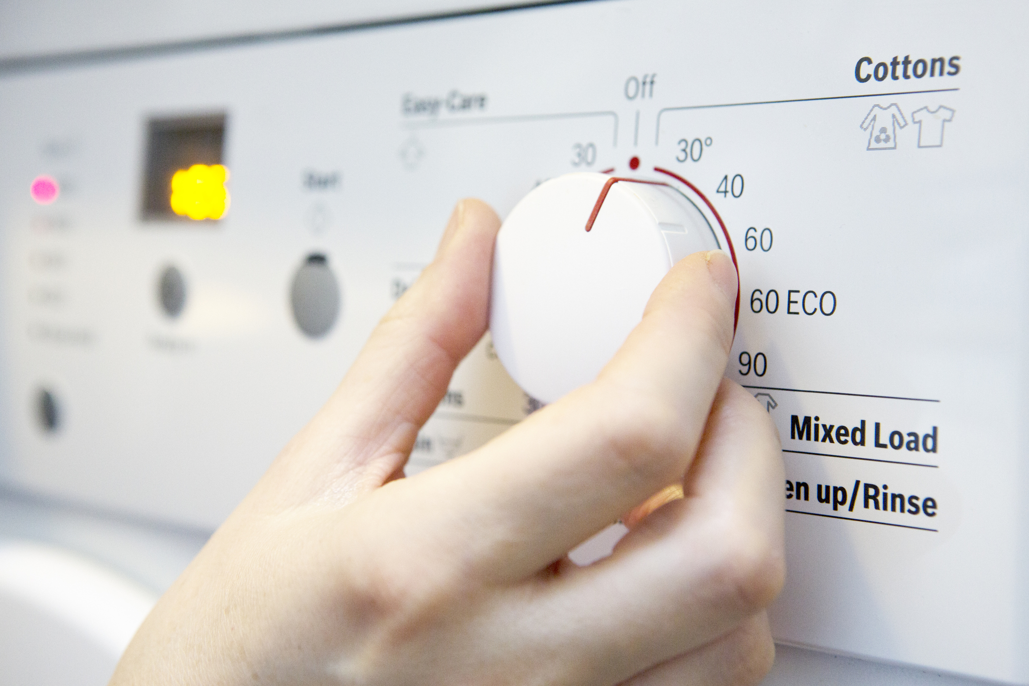 Choisir un programme basse température permet d'économiser sur sa lessive une personne est en train de régler une machine à laver sur le programme à 30°