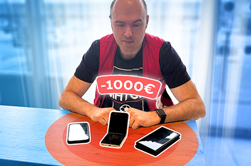 Les smartphones à - de 1000 euros permettent d'accéder au meilleur de la techno Vendeur Darty devant une table avec 3 telephones portables